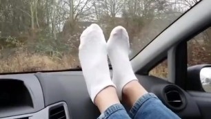 Blonde goddess shows her sexy white socked feet on car dash board